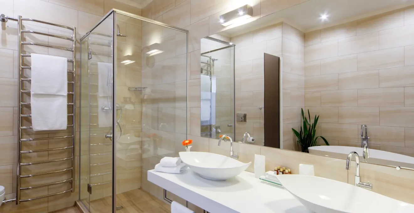 Plombier à genoux découpant un tuyau en acier galvanisé corrodé dans le mur ouvert d'une salle de bain de duplex montréalais en rénovation.